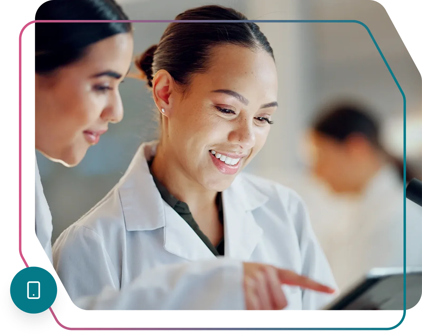 Two clinicians in lab coats smiling while reviewing patient results on a tablet